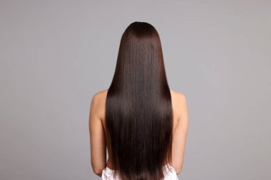 Açık gri arkaplandaki katman prosedüründen sonra güzel pürüzsüz saçlı bir kadın.