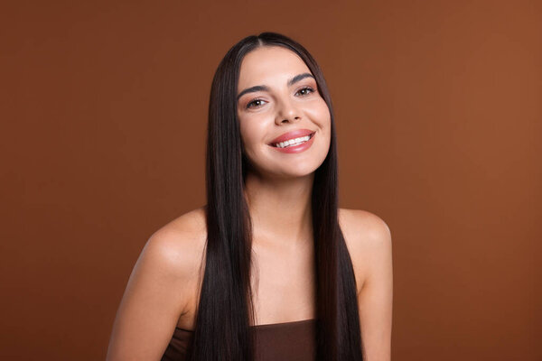 Woman with beautiful smooth hair after lamination procedure on brown background