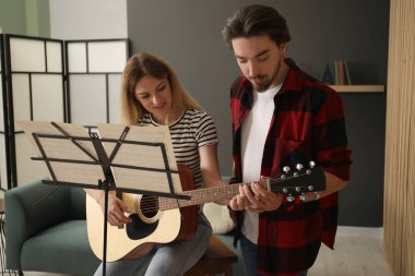 Öğretmenim kadınlara içeride gitar çalmayı öğretiyor.