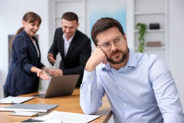 Meslektaşının ofisteki başarısını kıskanan, seçici odaklanan bir adam.