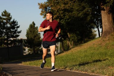 Spor giyimli atletik genç adam dışarıda koşuyor, mesaj için yer var.
