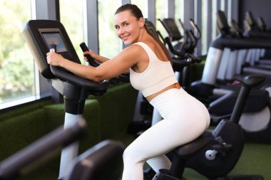 spor salonunda egzersiz bisikleti eğitim gülümseyen kadın