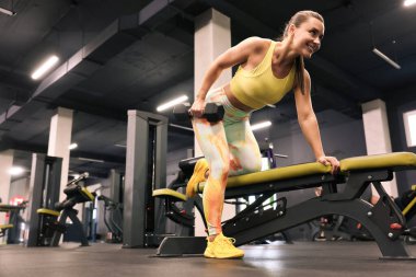 Spor salonundaki halterde halterle gülümseyen kadın eğitimi, düşük açı. Metin için boşluk