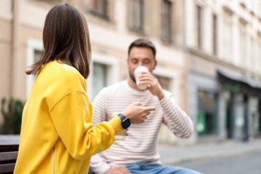 Paket kahve. Şehir caddesinde kağıt bardakta içki içen çift, seçici odaklı. Metin için boşluk