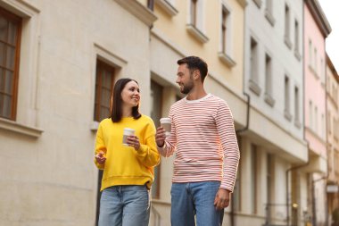 Paket kahve. Kağıt bardaklı bir çift şehir caddesinde yürüyor, düşük açılı.