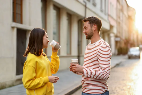 Paket kahve. Şehir caddesinde kağıt bardak içen bir çift.
