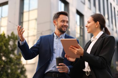 Paket kahve. Açık havada buluşurken kağıt bardak içen bir adam ve iş ortağı. Düşük açı.