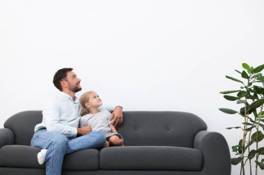 Baba ve kızı evdeki kanepede birlikte vakit geçiriyorlar. Metin için boşluk