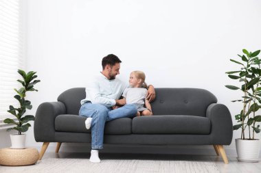 Baba ve kızı evdeki kanepede birlikte vakit geçiriyorlar.