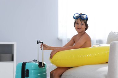 Denizde tatilin hayalini kuruyorum. Dalış maskesi, paletleri, şişme yüzüğü ve bavulu olan küçük çocuk.