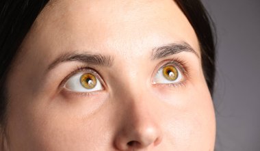 Açık gri arka planda güzel gözleri olan kadın, yakın plan.