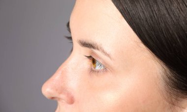 Açık gri arka planda güzel gözleri olan kadın, yakın plan.