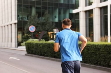 Spor giyimli bir adam dışarıda koşuyor.