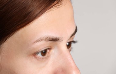 Açık gri arka planda güzel gözleri olan bir kadın, yakın plan. Metin için boşluk