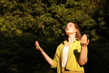 Doğadaki aurasını iyileştirmek ya da iyileştirmek için meditasyon yapan bir kadın.