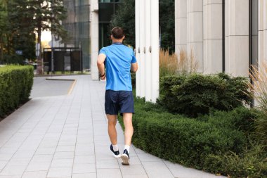 Spor giyimli bir adam dışarıda koşuyor.