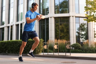 Adam açık havada koşarken fitness izleyicisini kontrol ediyor, metin için boşluk