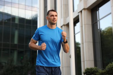 Spor giyimli bir adam açık havada koşuyor, düşük açılı.