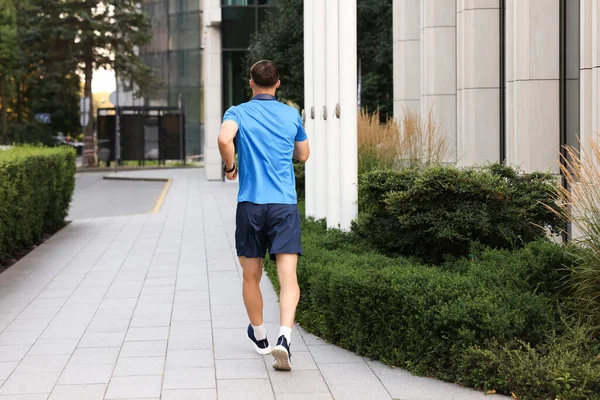 Spor giyimli bir adam dışarıda koşuyor.