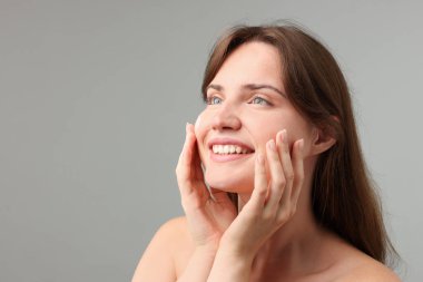 Beautiful woman with cream on her face against gray background. Space for text