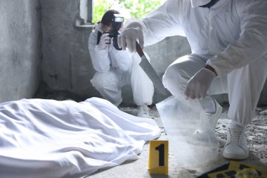 Adli tıp uzmanları terk edilmiş binanın içinde cesetle birlikte olay yerinde çalışıyorlar.