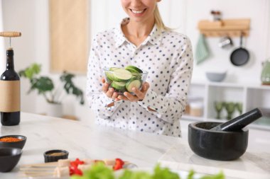 Mutfaktaki masada kabak dilimleri ile gülümseyen kadın, yakın plan.
