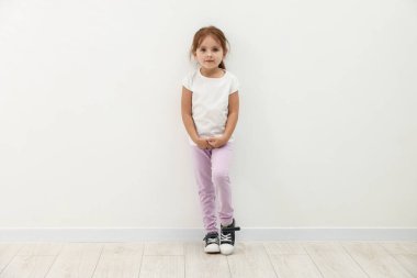 Beyaz duvarın yanında duran tatlı küçük kız.