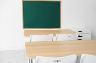 Boş yeşil karatahta, sınıfta masalar ve sandalyeler