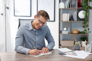 Man writing in planner at wooden table indoors