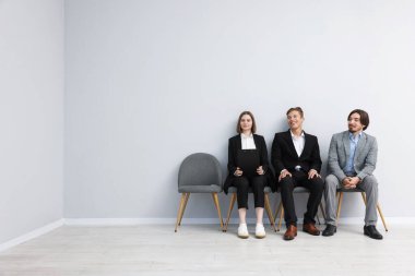 İnsanlar içeride sandalyede kuyrukta bekliyorlar.