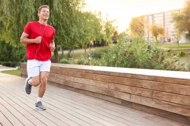 Şehir caddesinde koşan kulaklıklı mutlu adam.