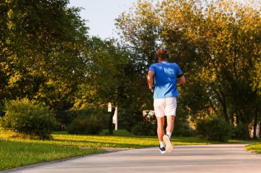 Güneşli bir günde parkta koşan adam, alçak açılı görüş.