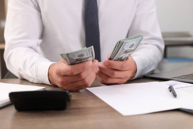 Ahşap masada dolar sayan adam, yakın plan.