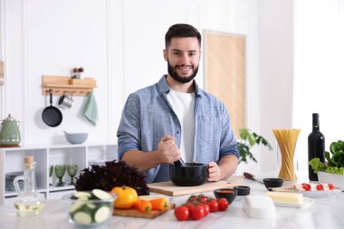 Mutfaktaki masada yemek pişiren gülümseyen adam.