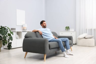 Evdeki kanepede dinlenen mutlu adam.