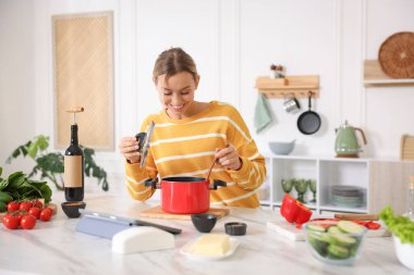 Mutfaktaki masada yemek yapan gülümseyen kadın.