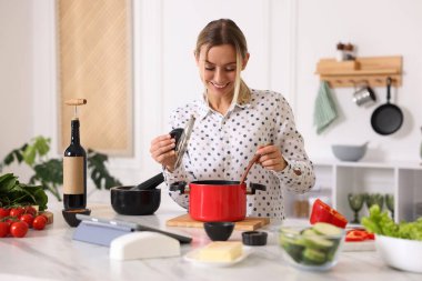 Mutfaktaki masada yemek yapan gülümseyen kadın.