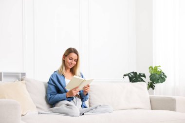 Evdeki kanepede kitap okuyan bir kadın. Metin için boşluk