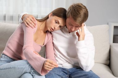 Evdeki koltukta hamilelik testi olan endişeli çift.