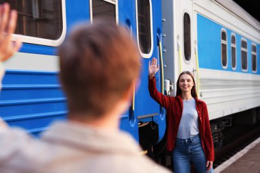 Hoşçakalın. Trenin yanında sevgilisine el sallayan bir adam, seçici bir odak noktası.