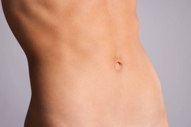 Gri arka planda düz göbekli kadın, yakın plan.