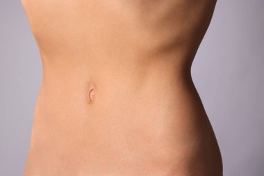 Gri arka planda düz göbekli kadın, yakın plan.