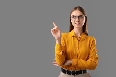 Kendine güvenen kadın gri arka plandaki bir şeyi işaret ediyor. Metin için boşluk