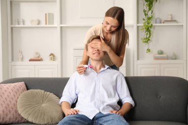 Mutlu genç bir kadın kocasına evde pozitif hamilelik testiyle sürpriz yapıyor.