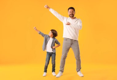 Baba ve oğul sarı arka planda eğleniyorlar.