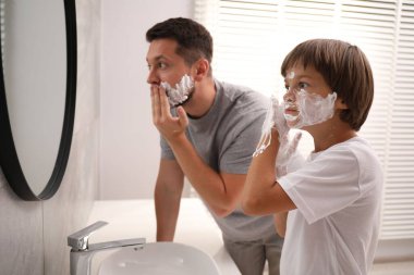 Baba oğul banyoda yüzlerine tıraş köpüğü sürüyorlar.