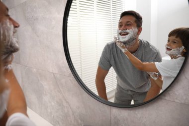 Banyoda yüzlerinde tıraş köpüğü olan baba ve oğul.