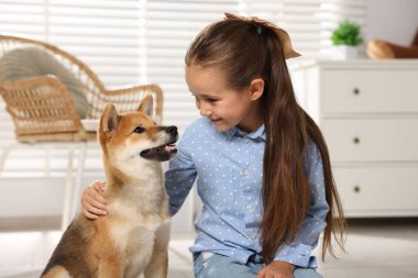 Evde köpeğiyle birlikte gülümseyen küçük bir kız. Çocuk ve hayvan