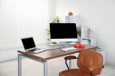 Ofisteki ahşap masada bilgisayar, dizüstü bilgisayar, tablet ve kulaklık ile modern işyeri