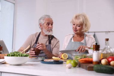 Yaşlı çift içeride birlikte yemek pişiriyor.